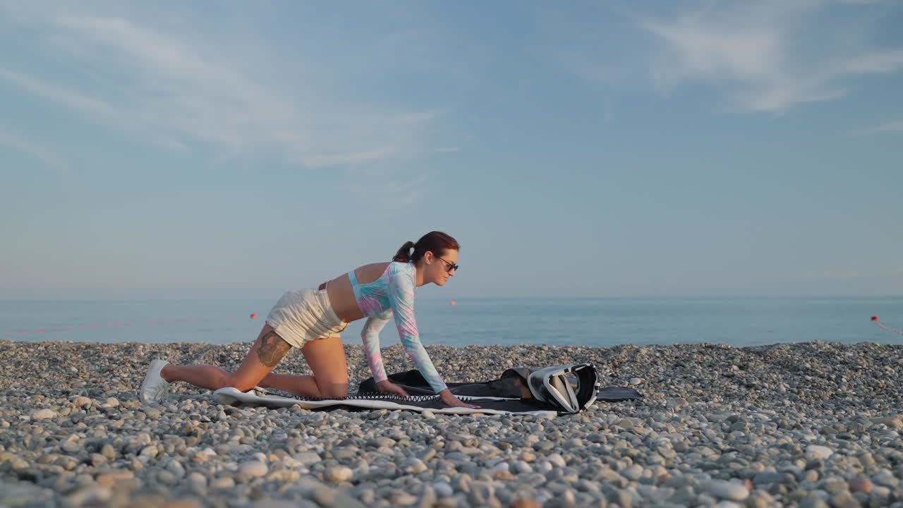 바위 해변 에서 부풀어올릴 수 있는 매트 를 준비 하고 있는 여자