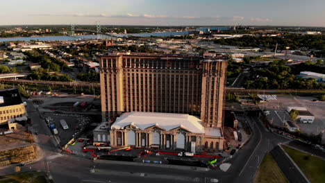 aerial footage of michigan central station in detroit during sunset with the ambassador bridge and windsor in the background