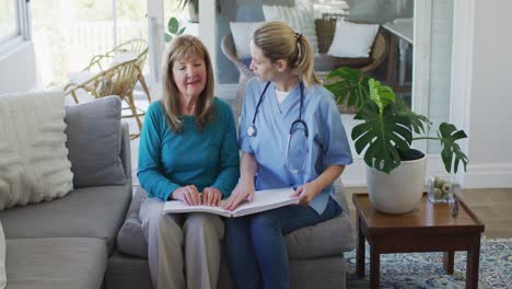 female health worker assisting senior woman to read braille book