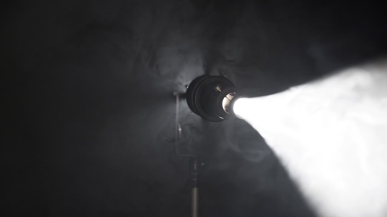 el haz de reflector gira lentamente y enciende la pantalla. focos de escenario y equipos de luz. focos sobre fondo negro, uhd