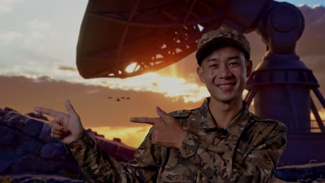 close up of asian man soldier smiling and pointing to side while standing with satellite dish