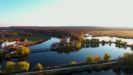 Serena-Vista-De-Drones-Al-Atardecer-Del-Delta-Del-Parque-Natural-De-Comana,-Un-Paisaje-Pintoresco-Con-Vegetación-Exuberante-Y-Edificios-Encantadores,-Rumania