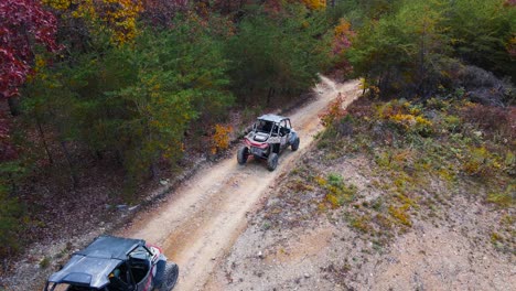 Aerial-shot-of-UTVs-driving-down-a-hill-while-trail-riding-during-autumn