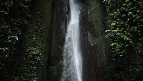 Slow-motion-panning-up-shot-in-front-of-a-gushing-Leke-Leke-Waterfall-in-Bali,-Indonesia-following-a-rain-storm