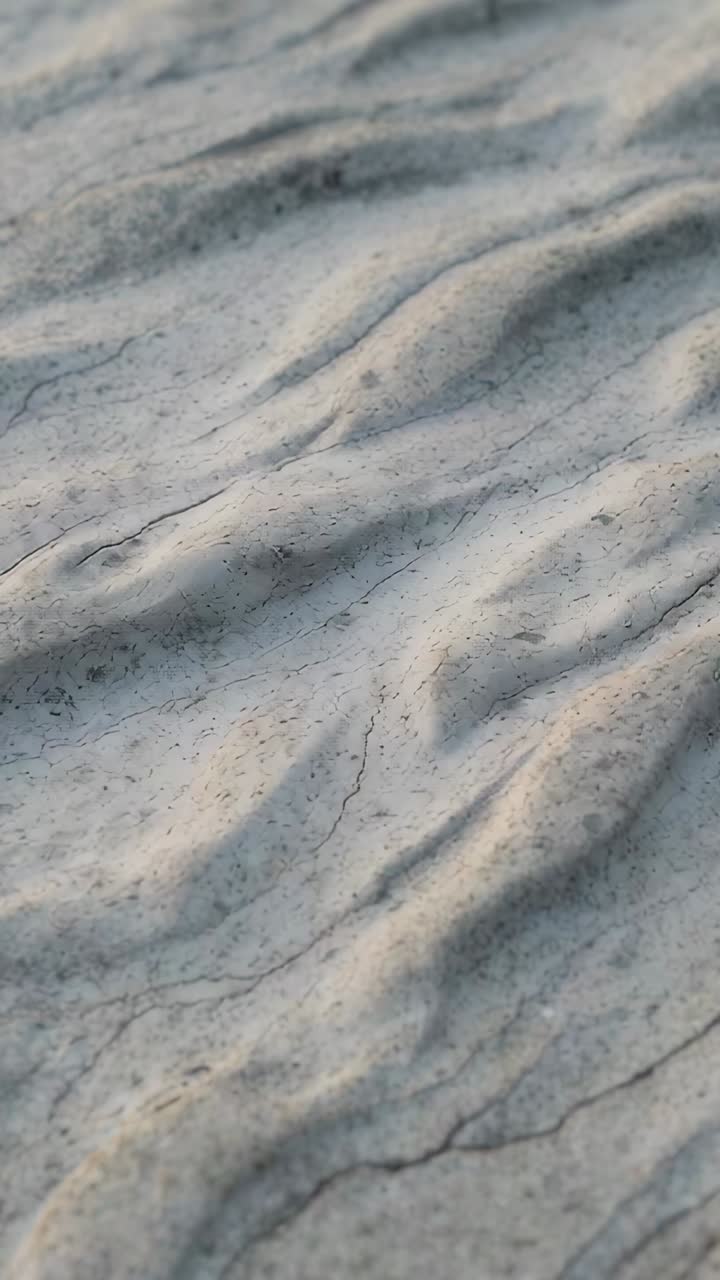 Vertical video: Camera sliding across macro rippled sand, revealing speckles, cracks to show ridges