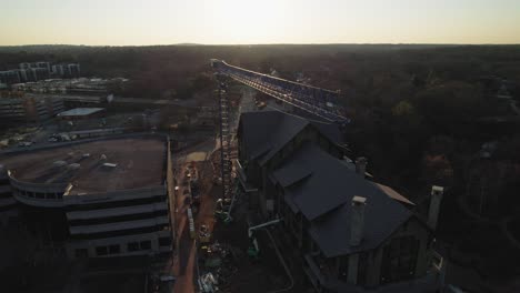 Drohnenumlaufkran-Auf-Baustelle-In-Morgensonne-Mit-Stark-Befahrener-Straße-Im-Hintergrund