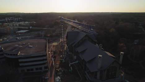 grúa en órbita de drones en el sitio de construcción en el sol de la mañana con una carretera muy transitada en segundo plano.