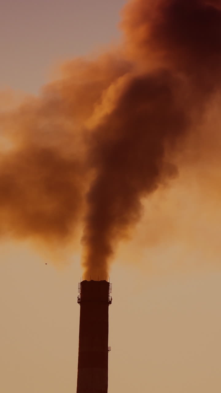 Air pollution by smoke coming out of two factory chimneys. Aerial view. Vertical video