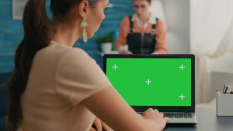 Back-shot-of-freelencer-woman-looking-at-laptop-with-mock-up-green-screen