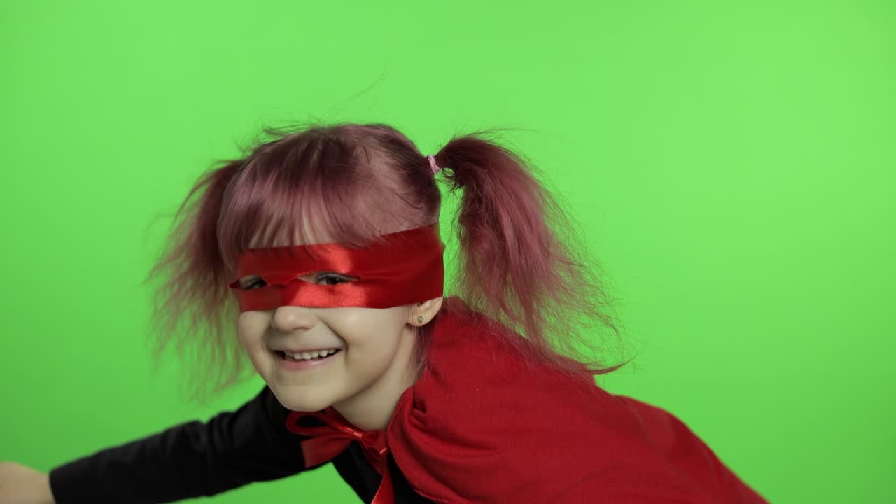 Funny child girl in costume and mask plays super hero. National superhero day