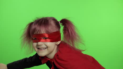 funny child girl in costume and mask plays super hero. national superhero day