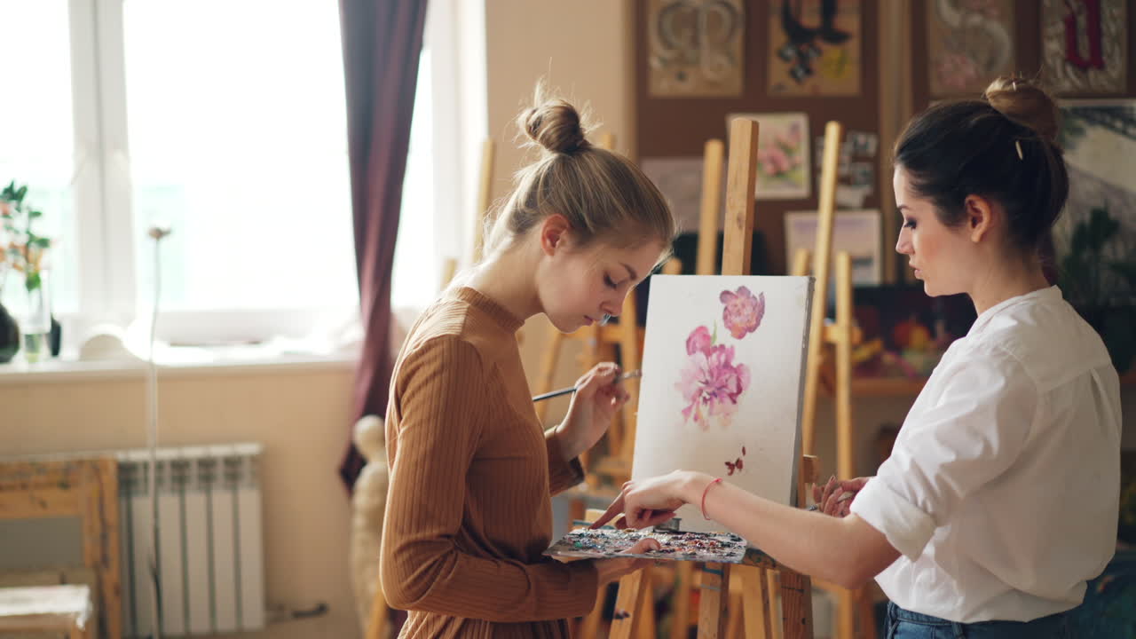 Two young women painting flowers in an art studio
