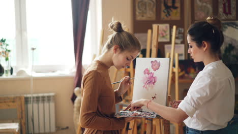two young women painting flowers in an art studio