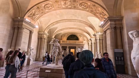 people exploring sculptures in louvre museum, paris