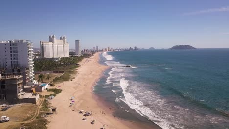 Aerial over golden sand beach with toursits in tropical resort town, Mazatlán, Mexico