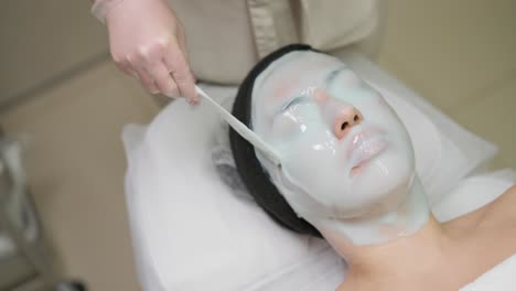 beautiful woman with facial mask at beauty salon