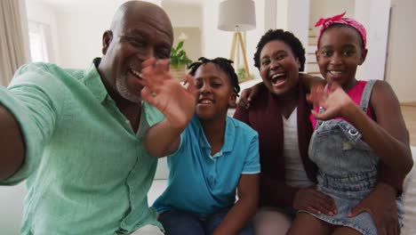 African-american-grandparents-and-grandchildren-waving-while-having-videocall-on-smartphone-at-home