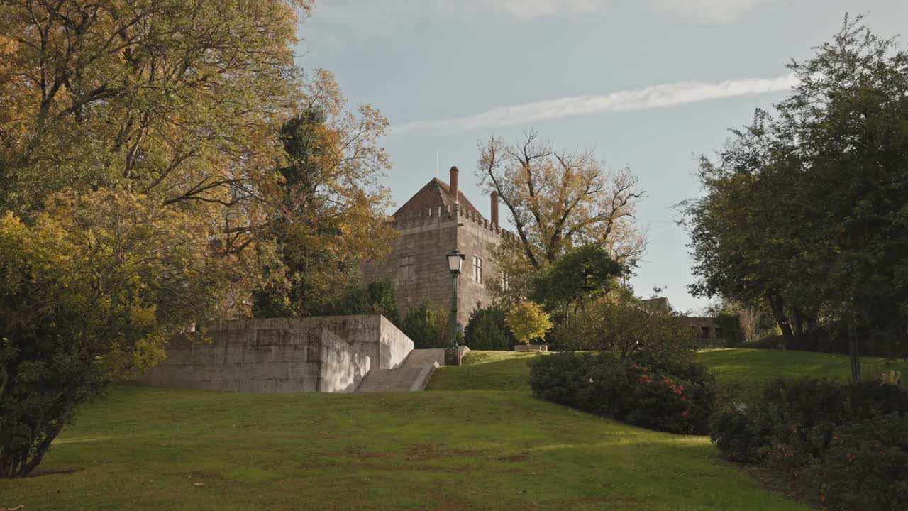 palazzo storico che si erge sopra tranquilli giardini e alberi autunnali a Guimarães, Minho