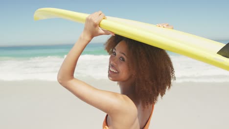 mujer afroamericana con una tabla de surf en la cabeza