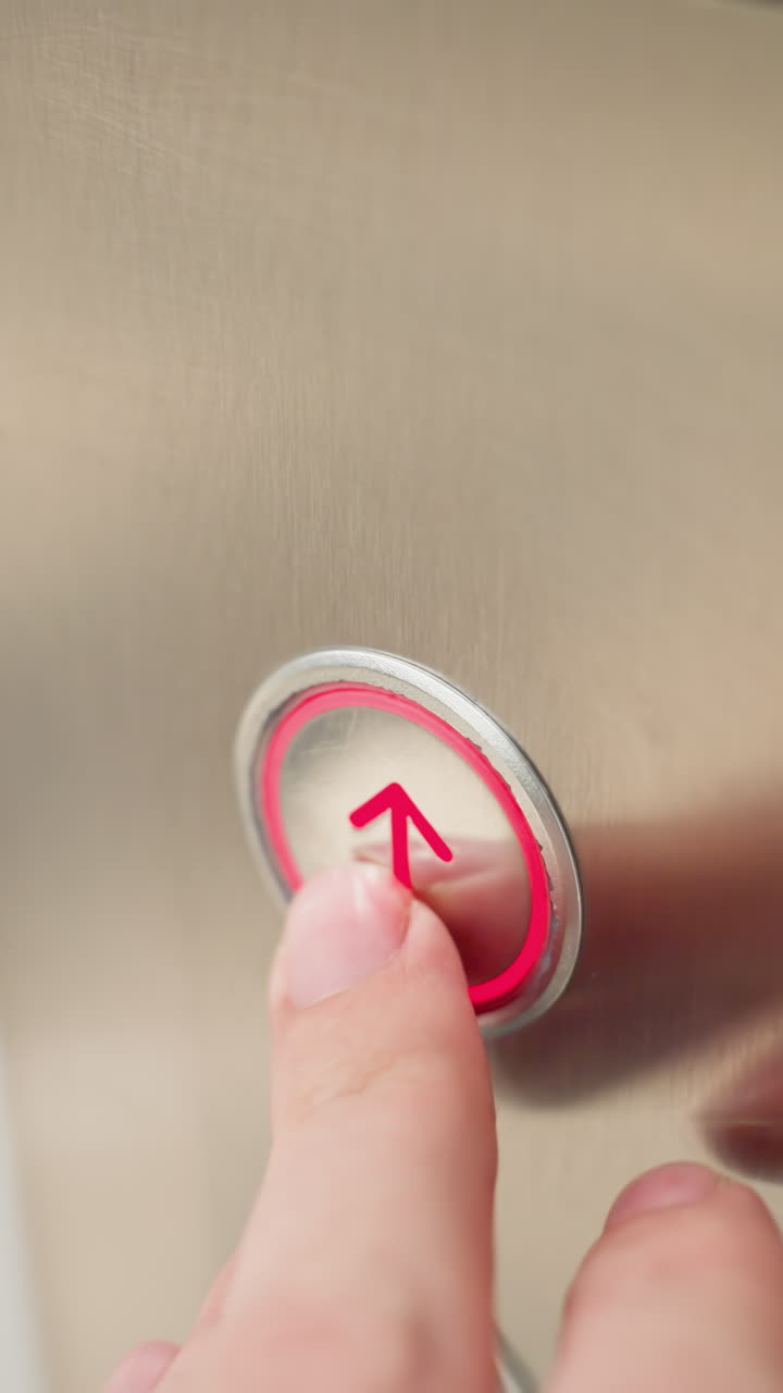 un panel de ascensor moderno con botones arriba y abajo. la escena muestra un dedo presionando el botón arriba, destacando la pantalla iluminada del número de piso y el elegante acabado metálico del panel
