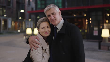 Retrato-De-Una-Pareja-Madura-Y-Elegante-Reunida-En-La-Ciudad-Abrazándose-Disfrutando-De-Una-Noche-Urbana-Juntos-Sonriendo-Feliz