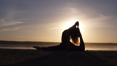 young pretty woman wearing yoga sportswear working out against sea, doing yoga or pilates exercise. variation of monkey god, splits, hanumanasana with backbend. full length