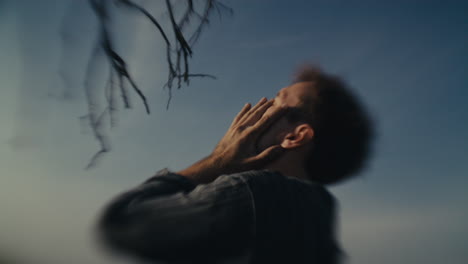 blurred portrait of a man with hands covering his face