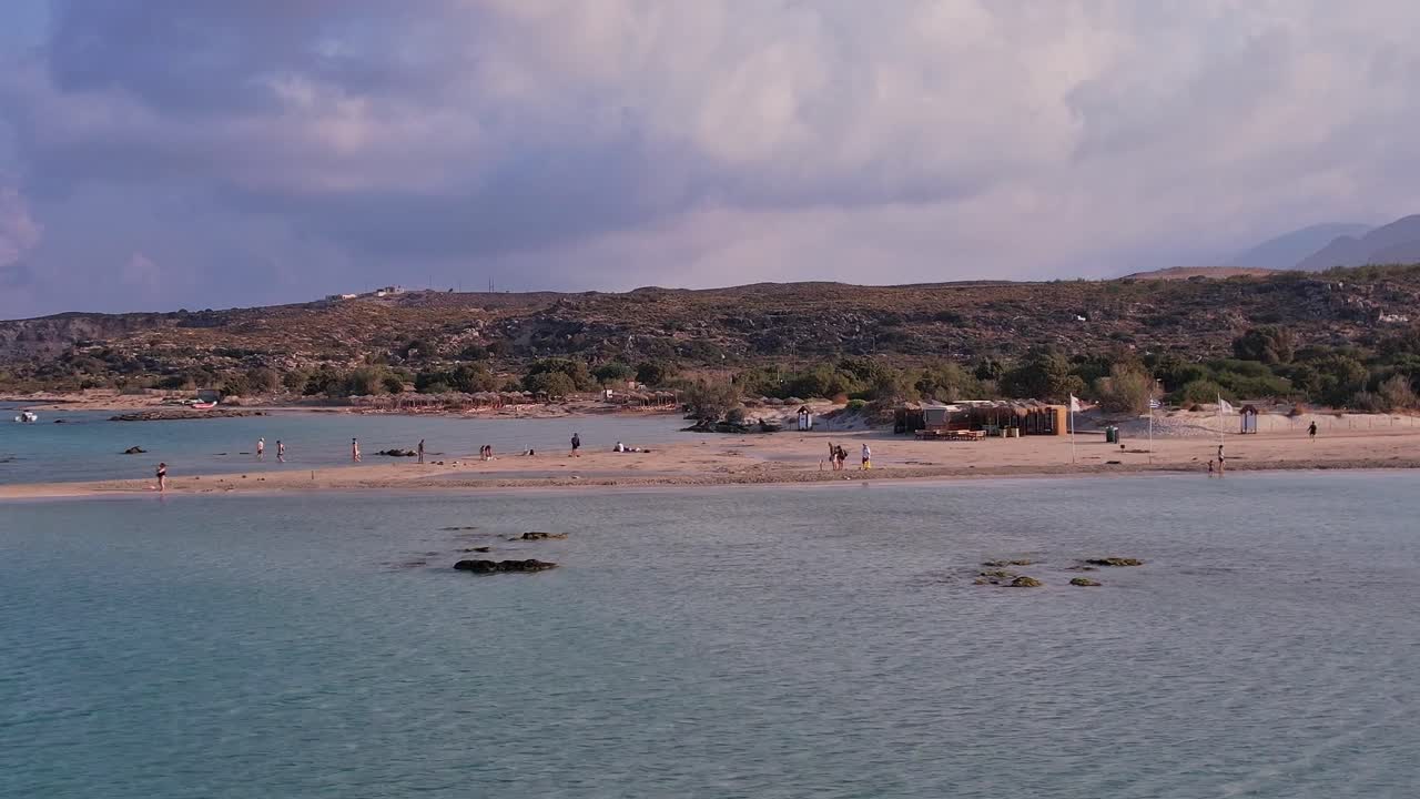 Luftfoto af folk, der slapper af på en sandstrand med turkisblåt hav