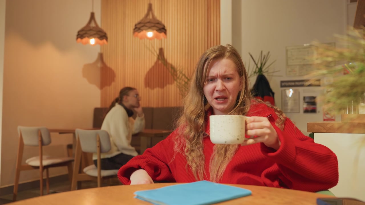 Ung kvinde kan ikke lide sin drink, mens veninde slapper af på café.