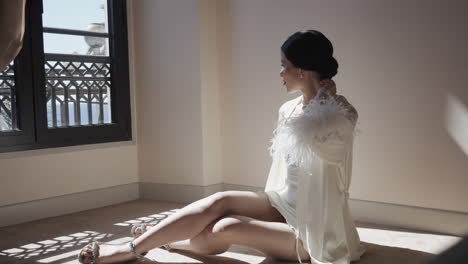 woman in a white robe sitting by the window