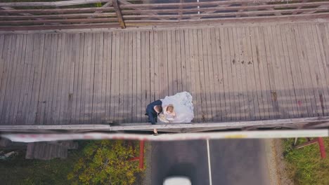 just-married-couple-near-railing-on-wooden-bridge-upper-view