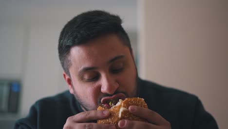 Man-eats-a-hamburger-with-his-mouth-wide-open