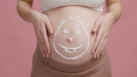 pregnant woman's belly with a face drawn with cream