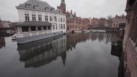 tilt up shot showing the canals of bruges with historic buildings in background during cloudy day