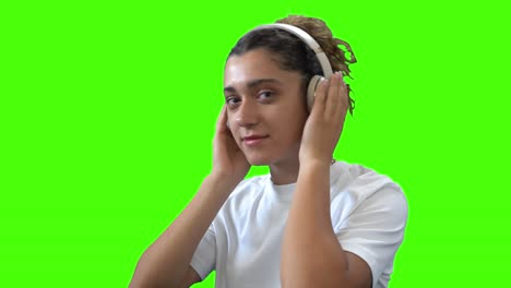 mujer joven sonriendo y bailando a la música de auriculares inalámbricos en la pantalla verde