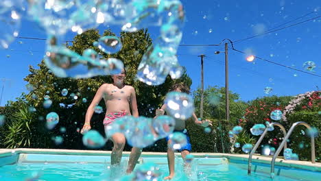 cheerful boys jumping into outdoor swimming pool on a summer day