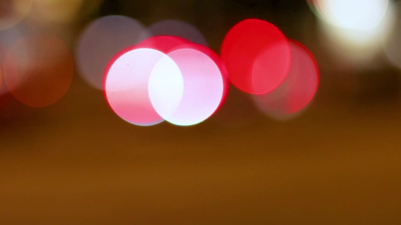 A series of red and white bokeh circles create a dynamic and abstract visual effect.