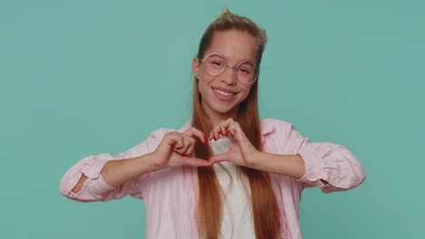 sonriente encantadora chica adolescente hace un gesto de corazón demuestra un signo de amor expresa buenos sentimientos