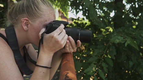 una joven fotógrafa compone un disparo en una escena sombreada de hojas