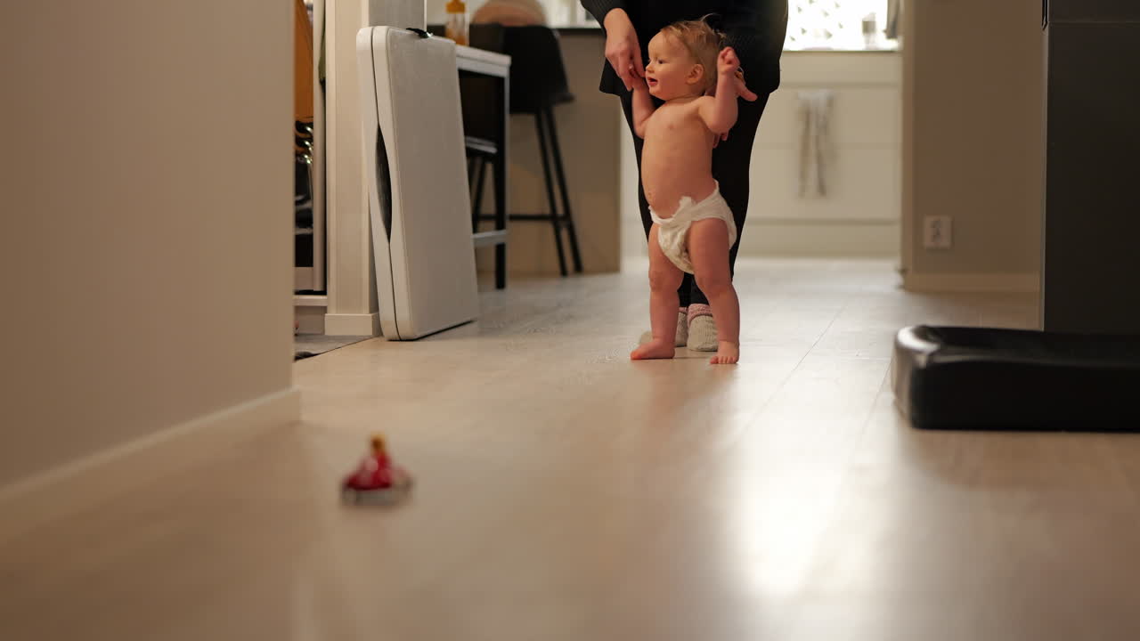 Very happy baby boy taking his first steps after a toy. Slow motion