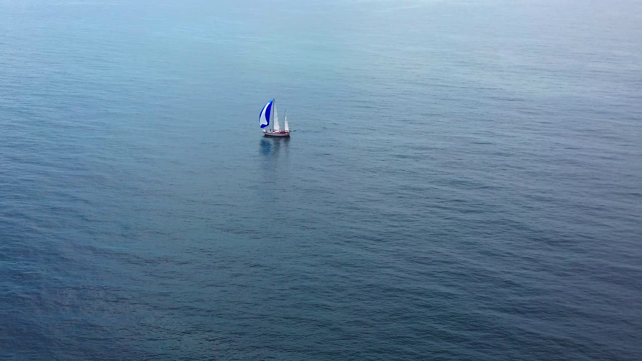 vista aérea de un barco de vela en el vasto océano azul, 4k