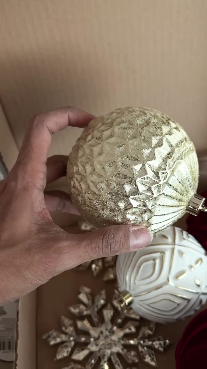 따뜻한 실내 조명 아래 손에 들고 있는 반이는, 질감 있는 크리스마스 장식품의 클로즈업