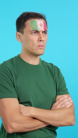 Man with mexican flag painted looking away with serious expression