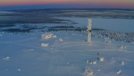 aerial view orbiting snow covered lapland remote cabin and communications tower rising above polar wilderness