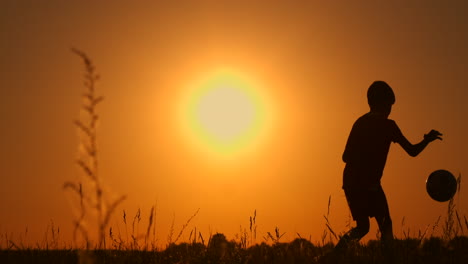 Un-Joven-Jugador-De-Fútbol-Entrena-Jugando-Con-Una-Pelota-Rellenando-Su-Pierna-Al-Atardecer-En-Cámara-Lenta-Durante-La-Hora-Dorada-En-El-Campo-Hasta-El-Atardecer.-Entrenando-Desde-El-Anochecer-Hasta-El-Amanecer.-Camino-Conceptual-Hacia-El-éxito