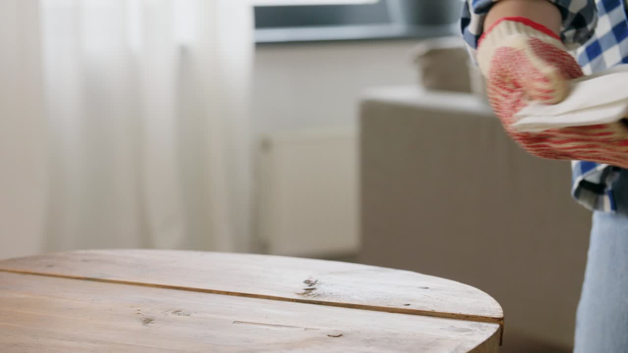 여성은 용매로 오래된 테이블 표면을 탈유합니다.