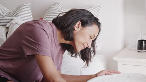 millennial mother gets up to check on her baby, sleeping in the crib beside her bed