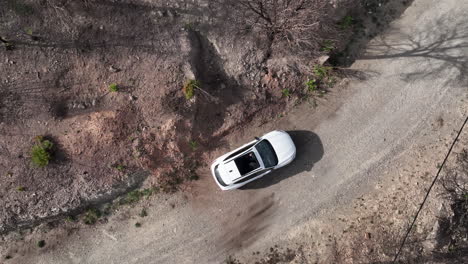 Vista-Aérea-De-Un-Vehículo-Blanco-Con-Techo-Abierto-Estacionado-En-Un-Camino-De-Grava,-Acercar