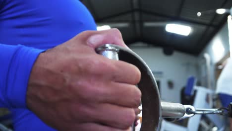 primer plano de la mano de un hombre haciendo una máquina de remo en el gimnasio