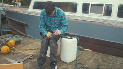 a young carpenter marking wood in front of a wooden boat